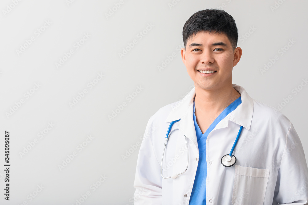 Male Asian doctor on light background