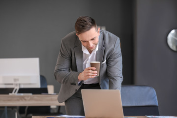 Canvas Print - Young man drinking coffee while working in office