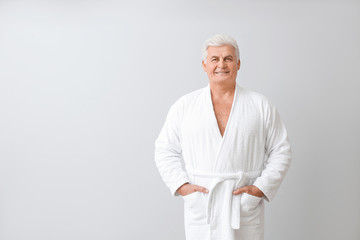 Wall Mural - Mature man in bathrobe on grey background