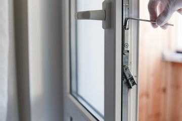 Man's hand makes adjustment of hardware of the uPVC door mechanism with an allen key.