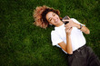 © maxbelchenko - Young woman sitting on the grass  in a city park and using a smartphone. Technology and modern lifestyle concept.