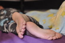 Feet Of A Sleeping Baby. On The Crib
