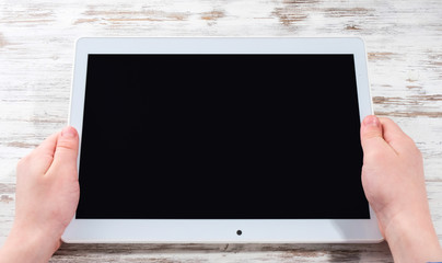 Hands with a tablet on the table. Girl holding a tablet in her hands.