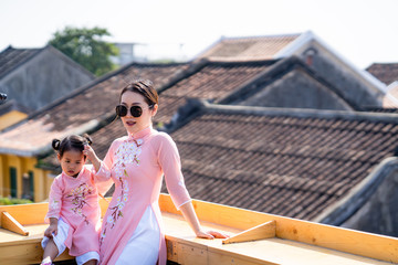 Mother and daughter with Vietnam culture traditional dress  standing at the rooftop in Hoi an.