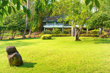 Tropical landscape with green lawn, trees and house at sunny day. Erawan National park, Thailand