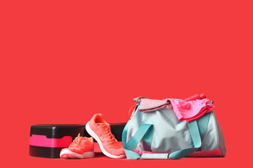 Bag with sportswear, equipment and shoes on color background