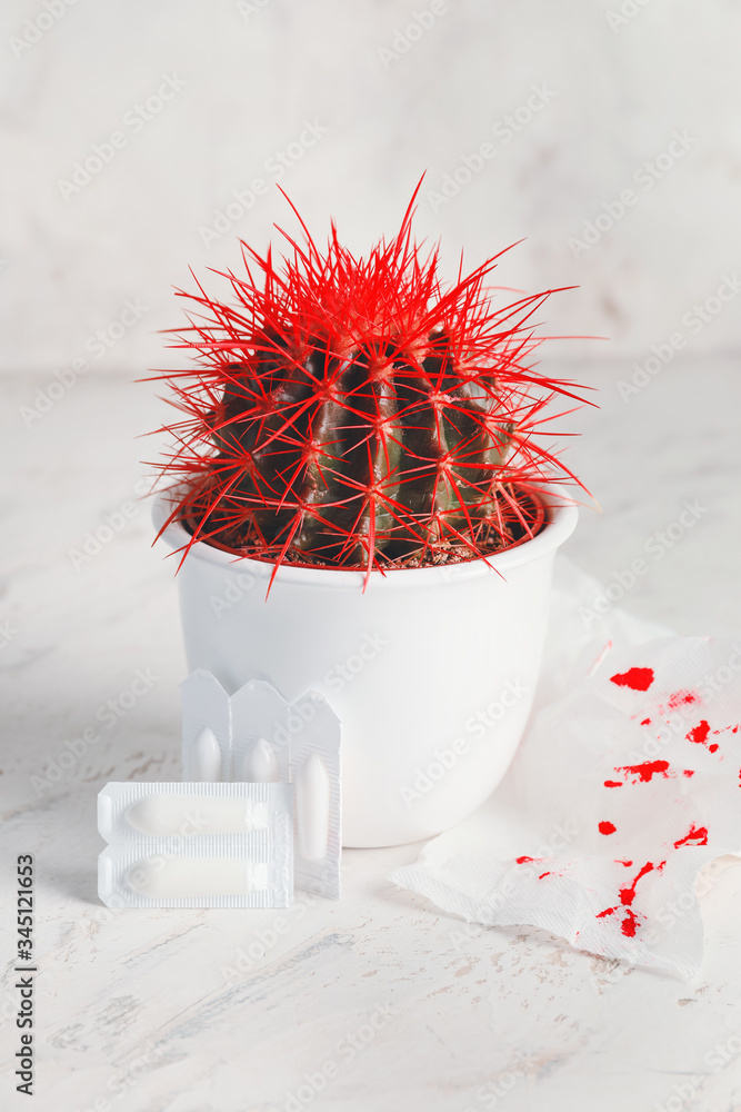 Cactus, toilet paper with blood spots and hemorrhoidal suppositories on light background