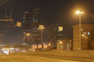 Wall Mural - Night city in the fog. Skyscrapers and illuminated highway. Almost no traffic. Coronavirus pandemic lifestyles.