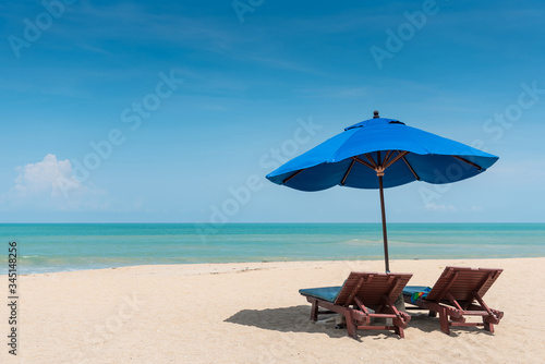 Fotografía Wooden beach bench under parasol umbrella on tropical island beach