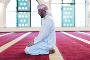 Poster - Young Arabic Muslim man  praying. Doing a dailly pray inside modern beautiful mosque.