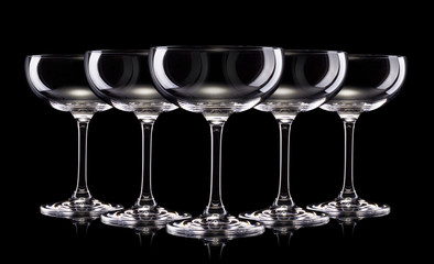 Wall Mural - Set of empty champagne glasses in a row isolated on a black background