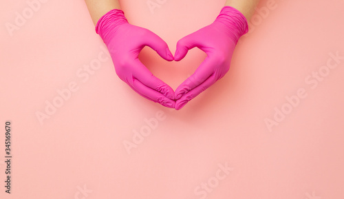Female hands in medical red gloves made in shape of heart on pink background. Banner with copy space for info about thanks to the doctors.