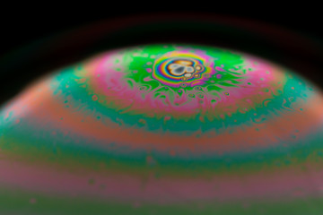 Psychedelic abstract planet from soap bubble, Light refraction on a soap bubble, Macro Close Up in soap bubble. Rainbow colors on a black background. Model of Space or planets universe cosmic galaxy.