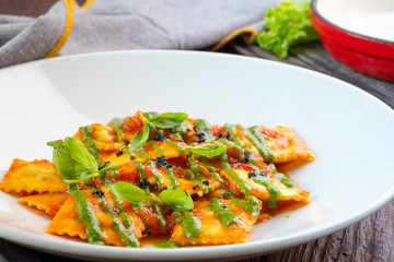 Wall Mural - Classic ravioli with tomato sauce and Basil leaves on a white plate, close up