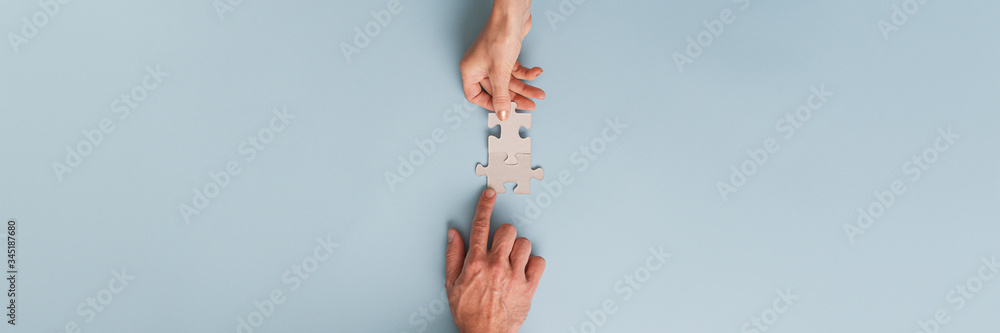 Business partners, businessman and businesswoman, joining two blank matching puzzle pieces - obrazy, fototapety, plakaty 
