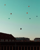 Fototapeta Lawenda - Scattered hot air baloons in the sky over buildings in the city