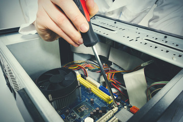 Close-up on the hands with screwdriver tool of the technician repairing a PC computer