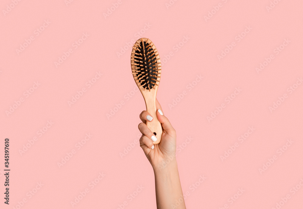 Closeup of millennial girl holding wooden hairbrush on pink background - obrazy, fototapety, plakaty 