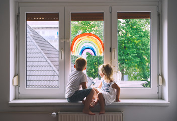 Children on background of painting rainbow on window.