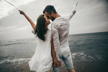 Wall Mural - Happy lovers have a cheerful vibes on sea beach at sunset 