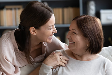 Wall Mural - Happy mature mother and adult daughter enjoying tender moment close up, looking at each other and holding hands, smiling young woman and older mum having fun together, two generations bonding