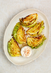 Wall Mural - Baked cabbage slices. Healthy grilled vegetable steaks with sauce and seasonings in a white plate. useful food. Vegan, vegetarian diet. Selective focus, top view