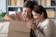 © fizkes - Surprised middle aged mother and adult daughter unpacking parcel together, looking in cardboard box, happy young woman with mature mum excited by delivery, received online store order