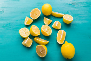 Freshly cut half and whole lemons on rustic aquamarine colour boards. Summer, vitamins and freshness concept.