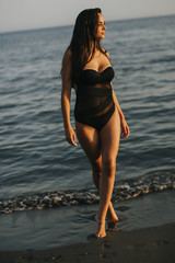 Canvas Print - Young woman walking in water at the beach