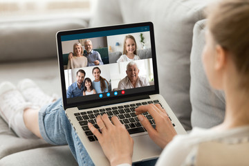 Wall Mural - Millennial girl relax on sofa at home talk chat with diverse relatives on video call using laptop gadget, young female rest on couch have webcam conference conversation with family on computer