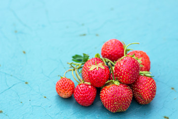 Natural organic food production. Freshly picked juicy strawberries on blue metal background. Heap of summer red berries. Homegrown, gardening and agriculture consept.