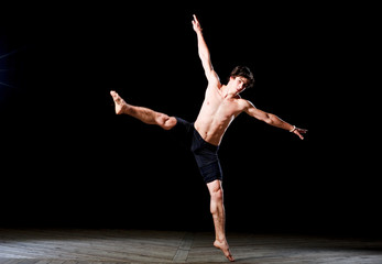 Wall Mural - Modern ballet style male dancer performs on high lighted stage .