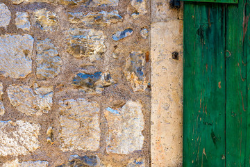 Wall Mural - Authentic house with a stone wall, with beautiful old open windows and with green shutters, and with vases on the window.