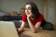 © Anatoliy Karlyuk - Beautiful stylsih young female with grayish hair and facial piercing sitting on carpet in front of open laptop computer, surfing internet using wireless connection, watching yoga tutorial online.