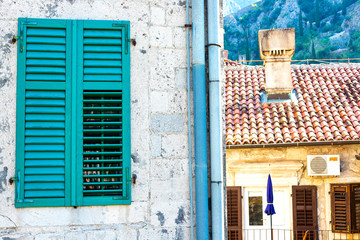 Wall Mural - Authentic house with a stone wall, with beautiful old open windows and with green shutters, and with vases on the window.