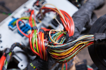 Canvas Print - Bunch of multi-colored electrical wires - blue, green, red and yellow, rewound with insulating tape leading to the connectors during network repair by an engineer or mechanic in a service or workshop