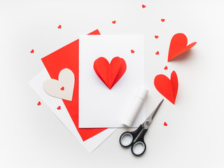 Wall Mural - Valentine's Day or Mother's Day greeting card. DIY holiday card with red paper volumetric heart, symbol of love and romance. Handmade card made with scissors, glue and colored paper.