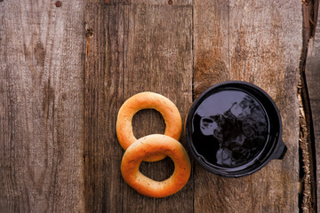 Fresh poppy bagel and hot thermo tea or coffee mug on a rustic brown wooden table. Breakfast or snack time. Top view with copy space. Camping food.