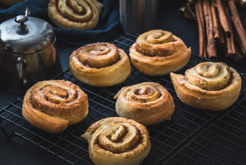 Wall Mural - Homemade cinnamon rolls on a colling rack with cinnamon sticks and sugar bowl