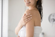 Close up of smiling young woman touch soft healthy glowing skin after shower or bath treatment, millennial Caucasian girl wrapped in towel do daily beauty procedures, apply cream, skincare concept