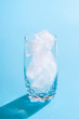 © YesPhotographers - Glass with ice cubes on blue background. Empty glass with ice