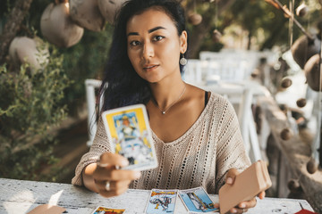 Wall Mural - Woman is reading Tarot cards sitting at the table outdoors