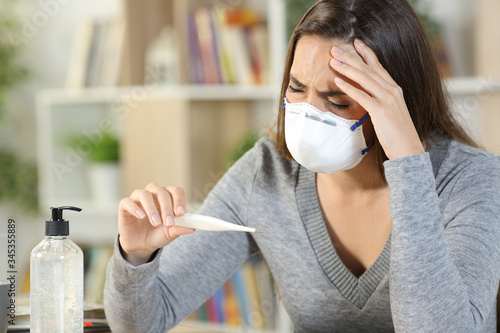Fotografía Sick woman with covid-19 symptoms holding thermometer at home