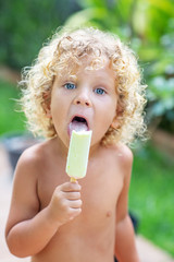 Wall Mural - Happy curly boy eating ice cream