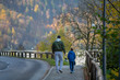 Father and son enjoy in walk by the road near forest in autumn