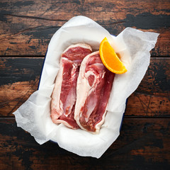 Wall Mural - Fresh raw duck breast fillets with orange wedge ready to cook on wooden table background