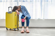 © Goffkein - Woman traveler with yellow suitcase affected by flight delay and cancelled travel and vacation holiday. Travel ban and traveling problems