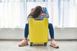 © Goffkein - Woman traveler with yellow suitcase affected by flight delay and cancelled travel and vacation holiday. Travel ban and traveling troubles