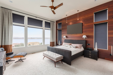 Large master bedroom in new luxury home with with hardwood accent wall and beautiful view