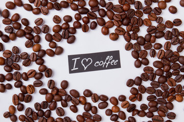 I coffee coffee flat lay. ROasted coffee beans scattered around on white isolated background.